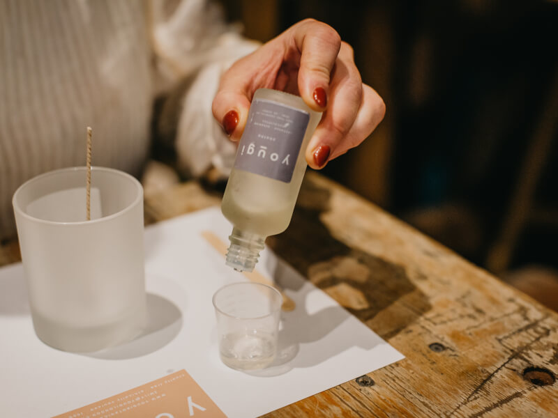 A woman pouring fragrance oil into a small jar